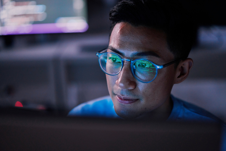 Web programmer or developer in front of computer in office at night