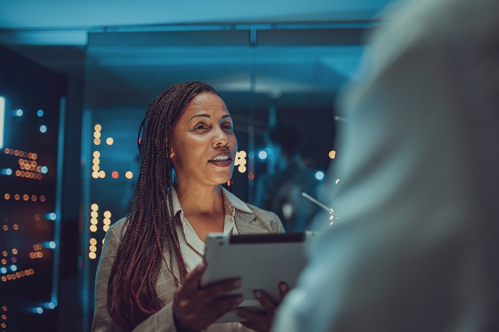 female maintenance engineer examining data on digital tablet in server room